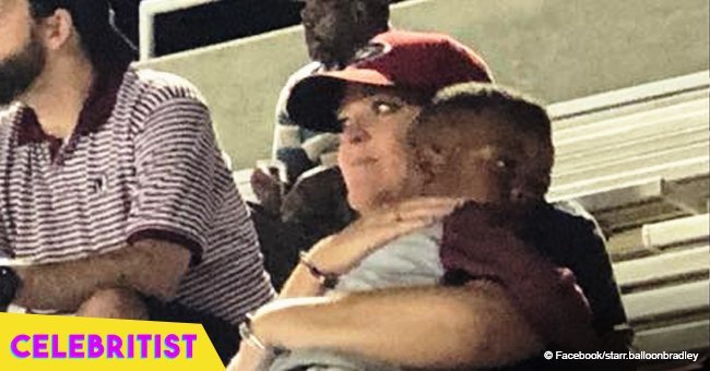 Heartwarming photos of little boy being cuddled by a stranger at football game go viral