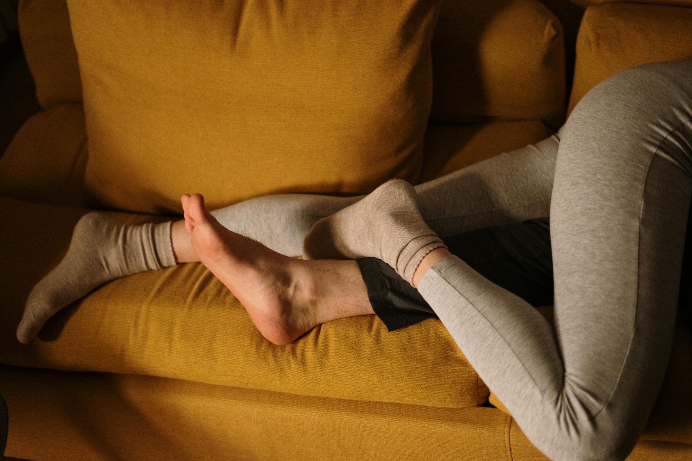 A couple's legs intertwined on a couch | Source: Pexels