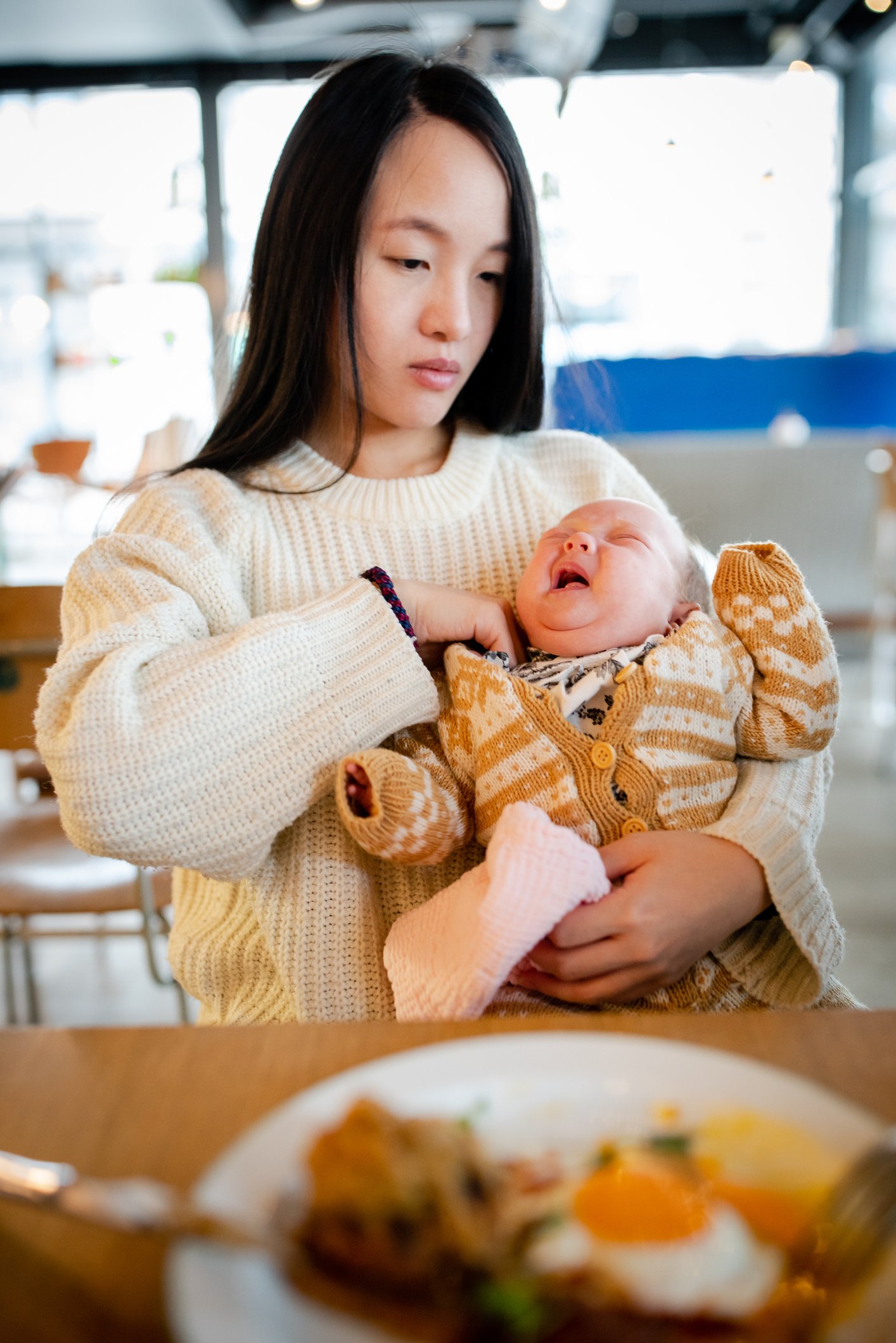 Une mère tient son bébé dans les bras dans un café | Photo : Getty Images