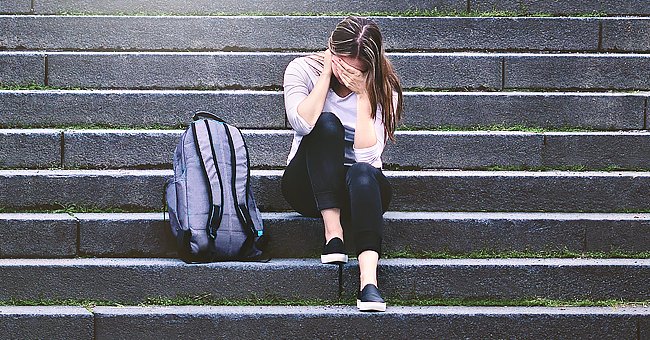 A teenage girl crying on the stairs | Photo: Shutterstock