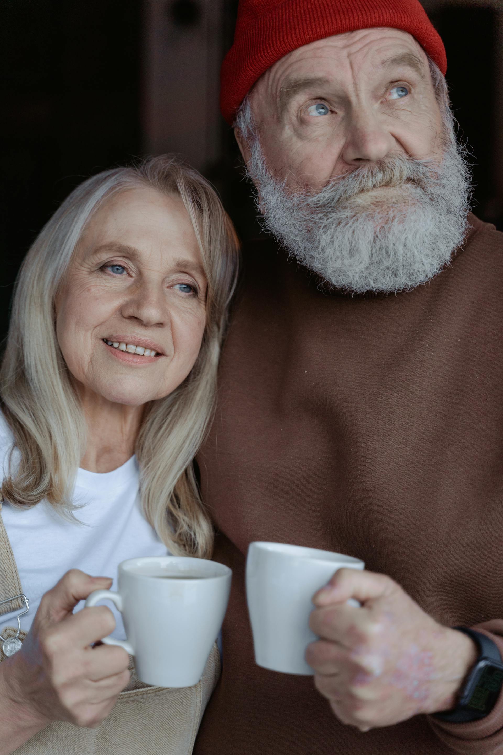 Smiling older couple holding ceramic mugs | Source: Pexels