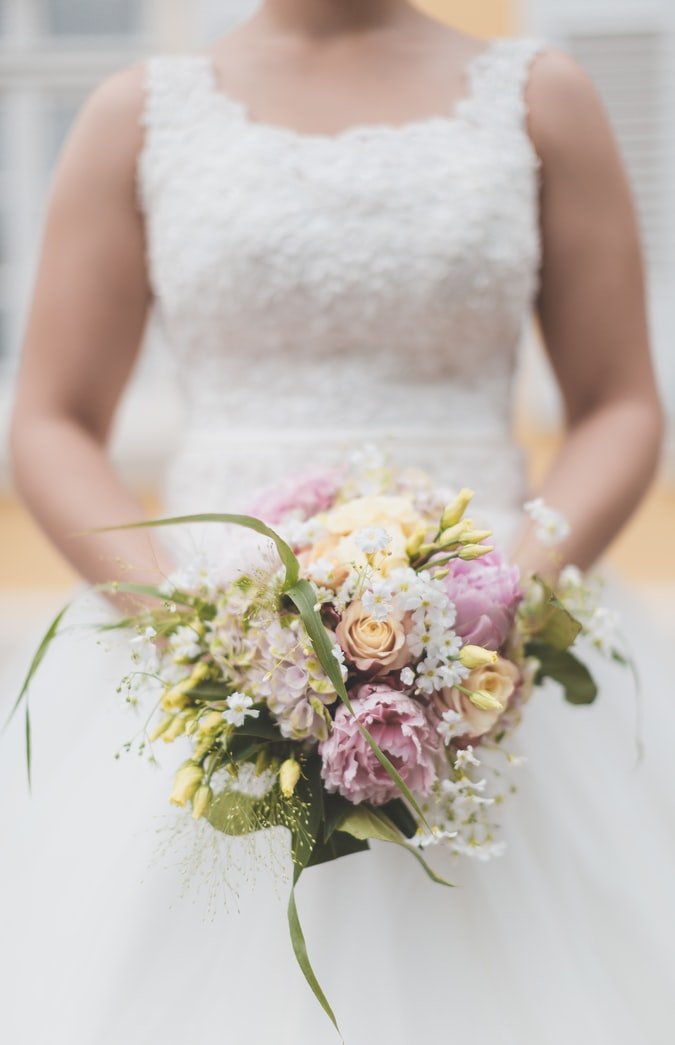 Una mujer vistiendo su traje de novia sosteniendo un ramo de flores. | Foto: Unsplash