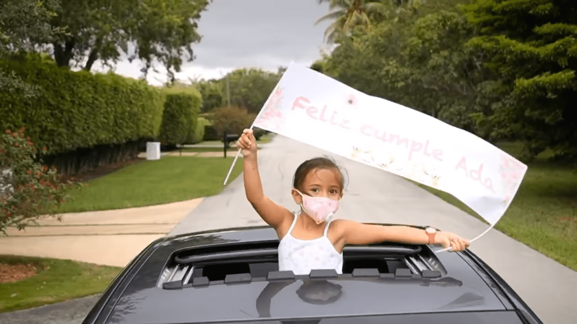 Una pequeña invitada agita un cartel de cumpleaños desde un coche. | Foto: Facebook/Toni Costa