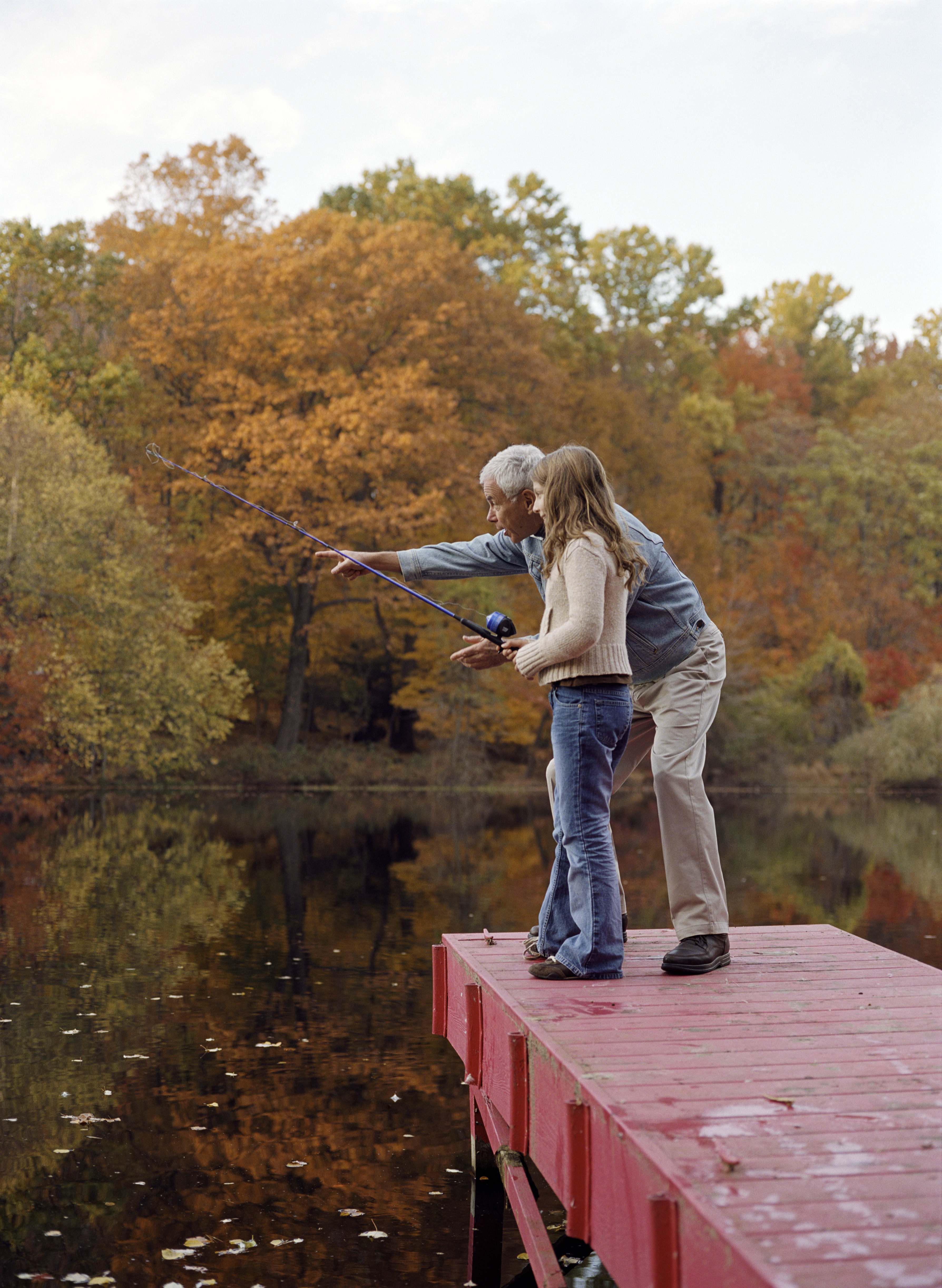 Grandfather and granddaughter (8-10) on dock, girl with fishing rod | Source: Getty Images