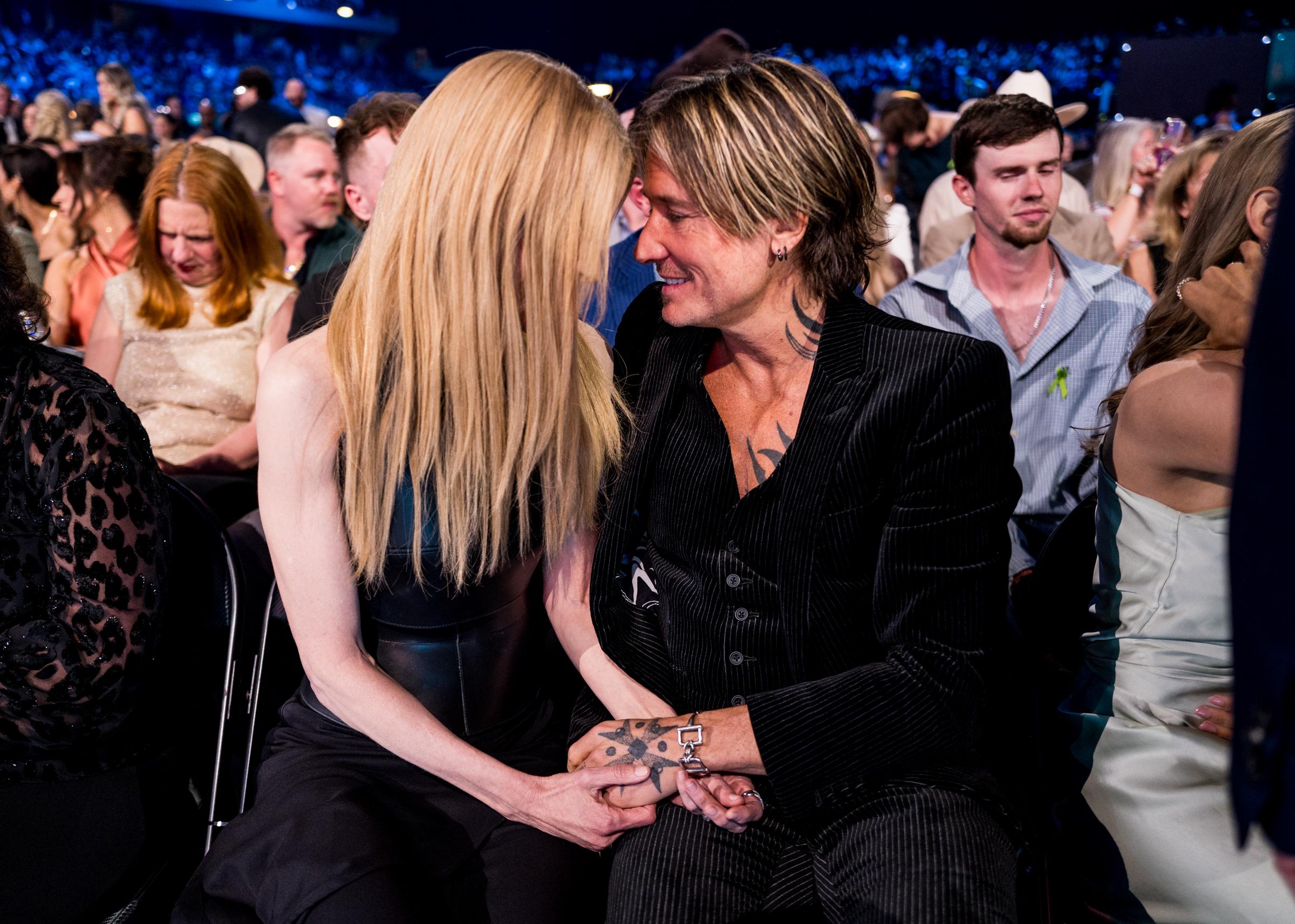In a rare unguarded exchange, Nicole Kidman and Keith Urban lean in and lock eyes from their seats inside the arena, smiling quietly as their hands remain tightly clasped.