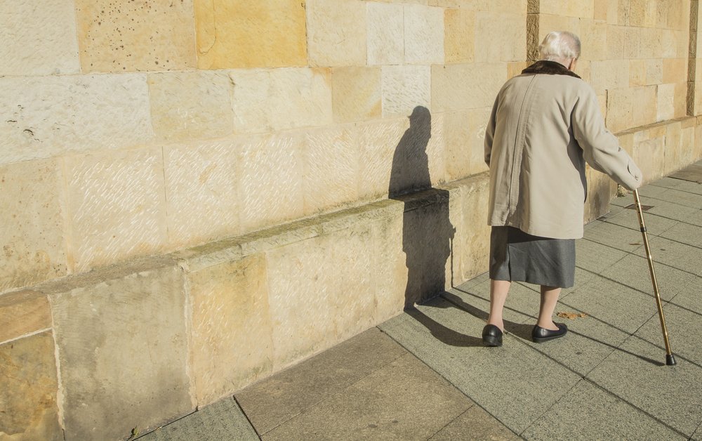 Anciana con un bastón caminando por una acera. | Foto: Shutterstock