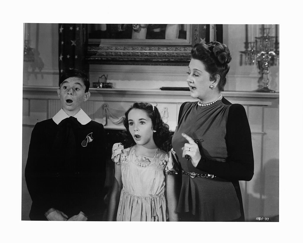 Carl Alfalfa Switzer and Elizabeth Taylor led in song by Catherine Doucet in a scene from the film "There's One Born Every Minute" circa 1942. | Photo: Getty Images