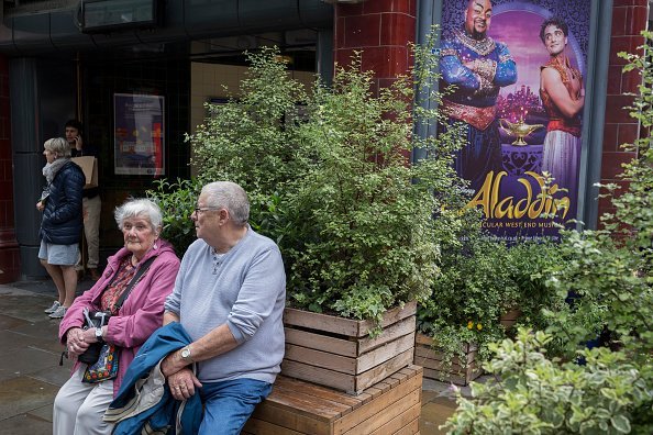 An elderly couple resting on a bench in front of Covent Garden Underground station.| Photo : Getty Images
