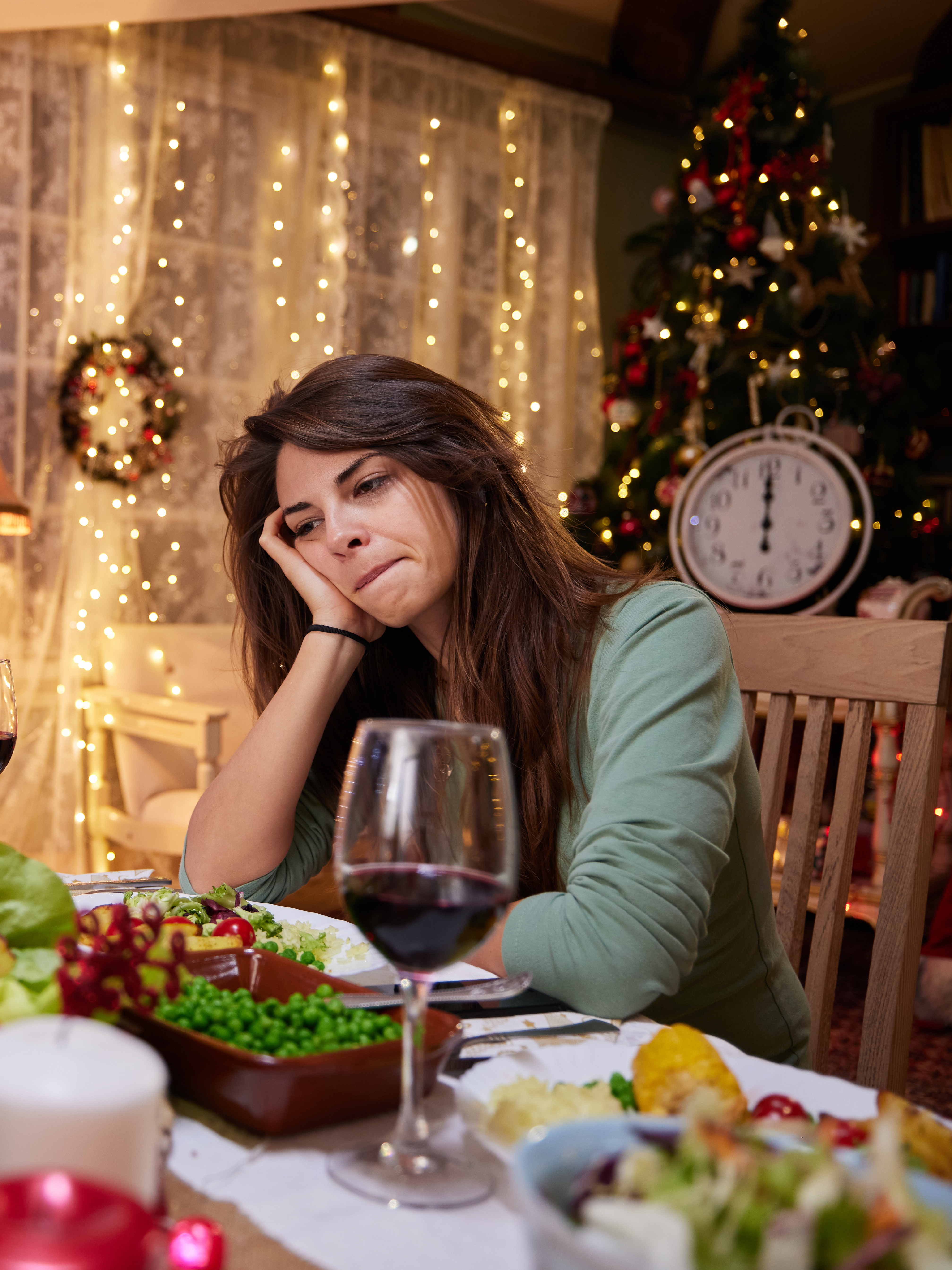 A sad woman sitting alone at a dining table on Christmas Eve | Source: Getty Images
