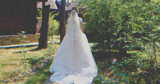 Mujer joven con su traje de novia posando de espaldas en un jardín. | Foto: Shutterstock