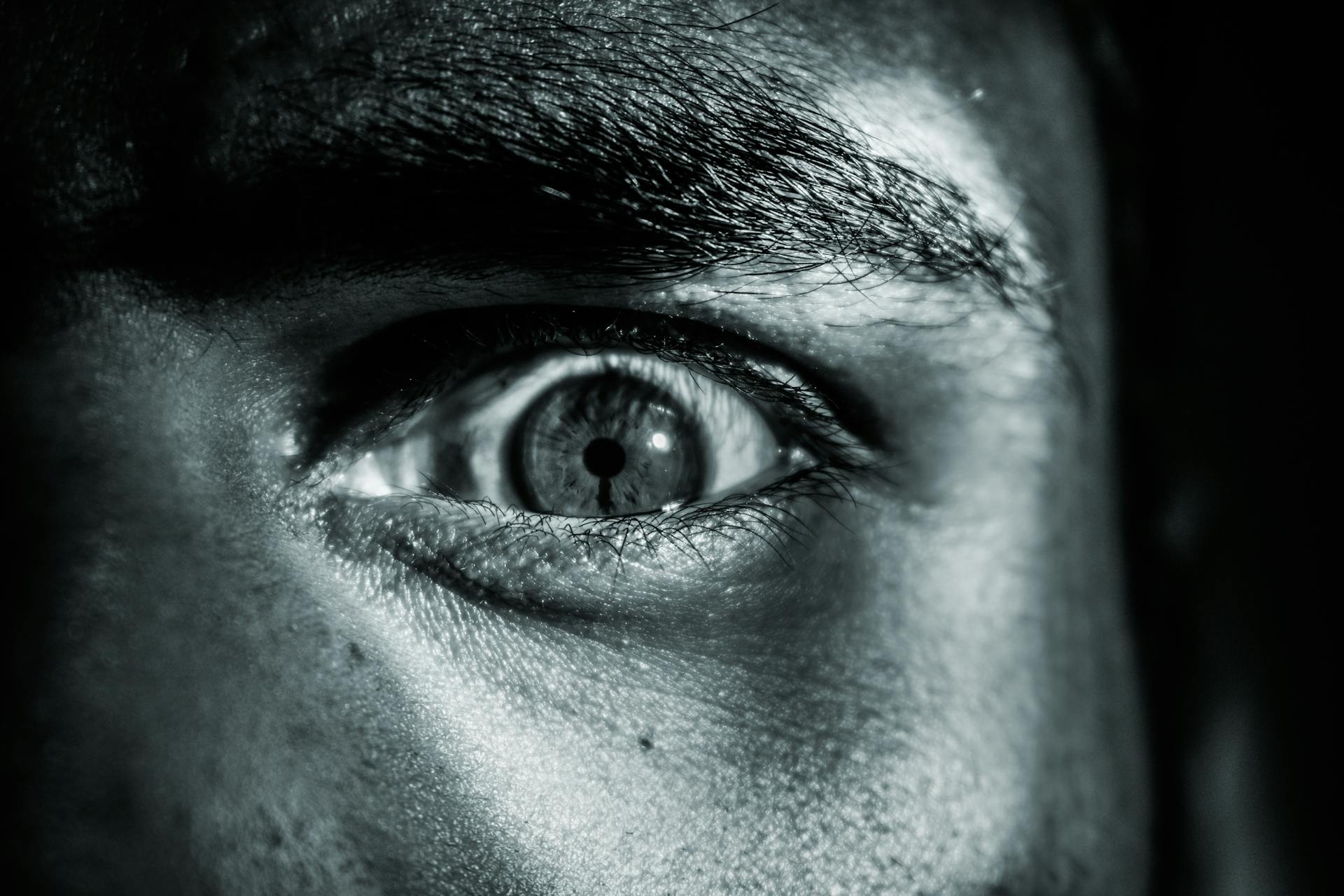 Close-up grayscale shot of an angry man's eye | Source: Pexels