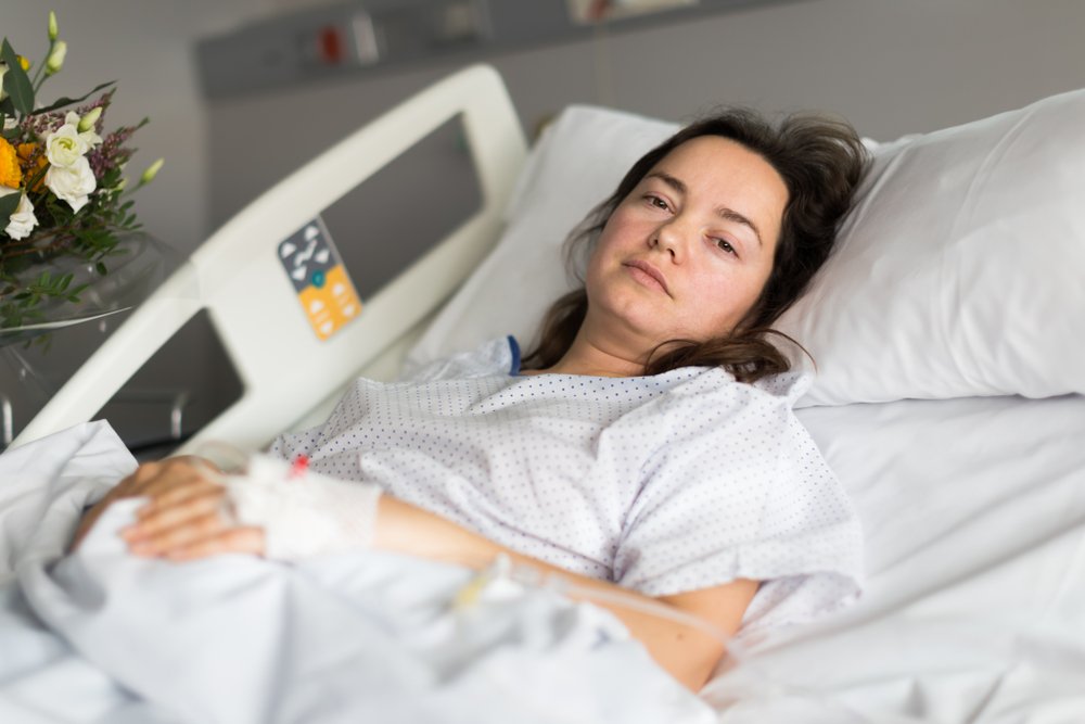 Ein Foto einer brünetten Frau, die auf einem Krankenhausbett liegt. | Quelle: Shutterstock
