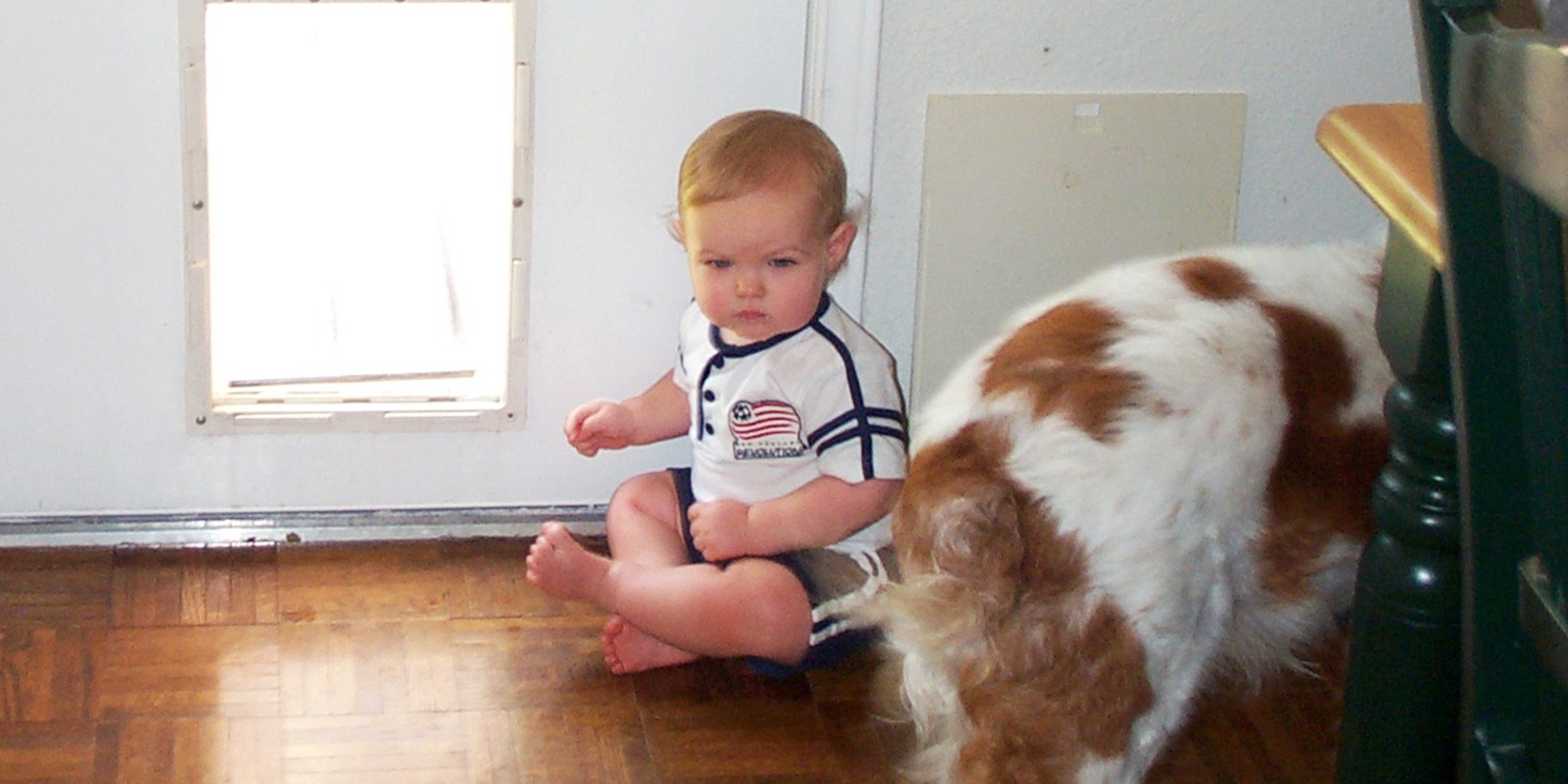 A child sitting next to a doggy door | Source: Flickr