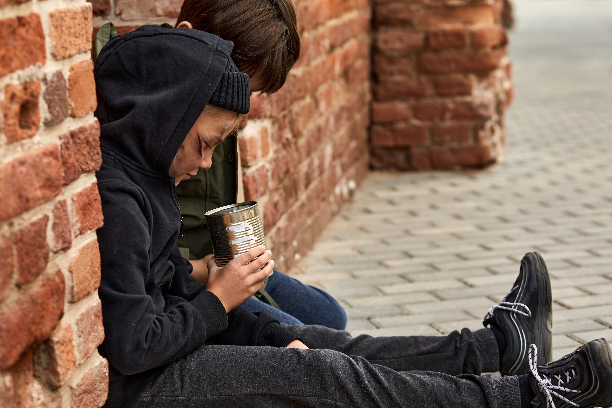 Two homeless boys counting their money in a tin can | Source: Shutterstock