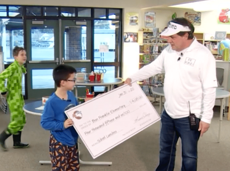 Keoni Ching hands out the check worth $4015 to his school to clear the lunch debt. | Source: YouTube/CBS 17