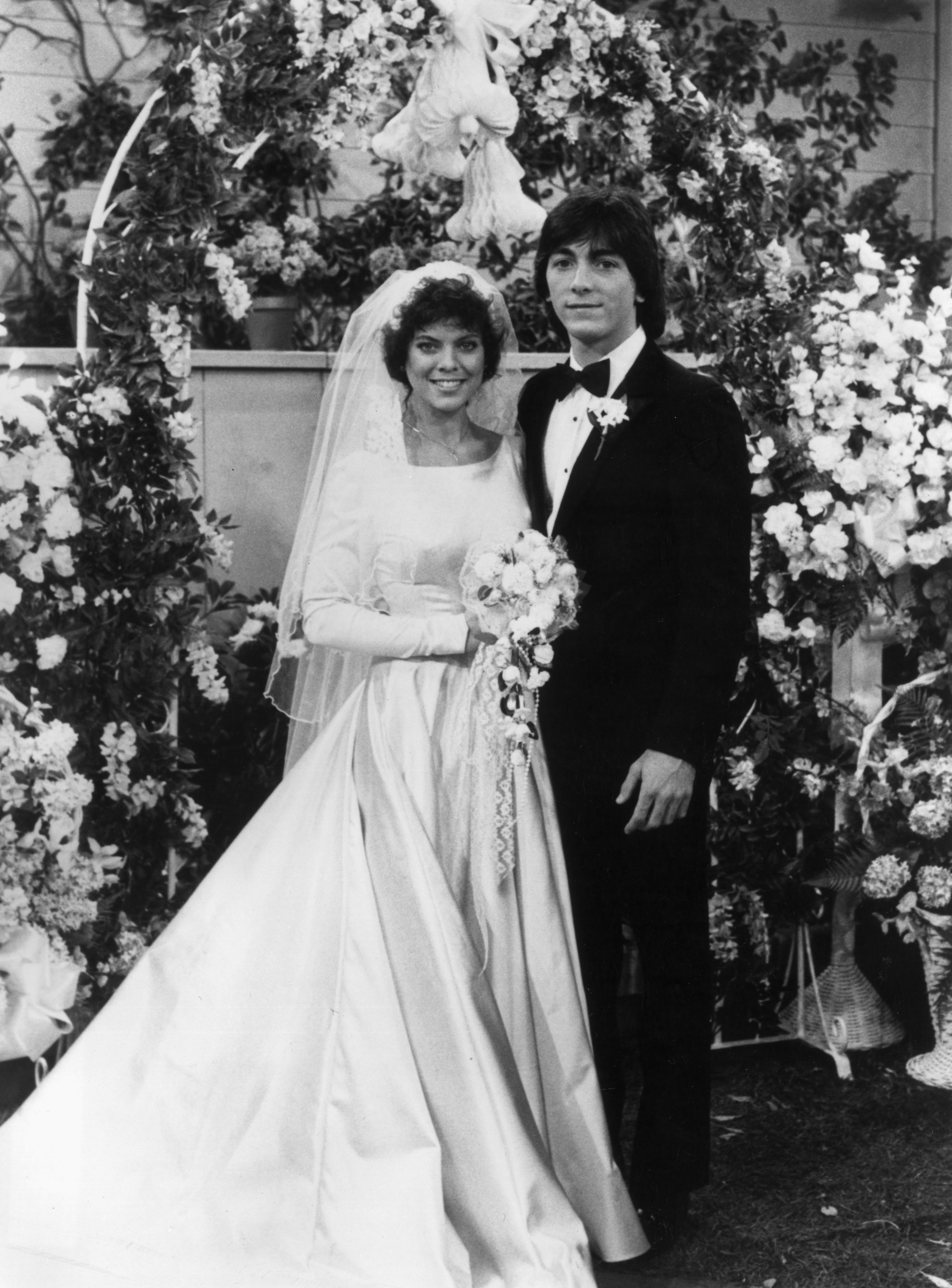 Erin Moran, wearing a wedding dress, and Scott Baio, wearing a tuxedo, posing at an altar in a promotional portrait for "Happy Days.'" / Source: Getty Images