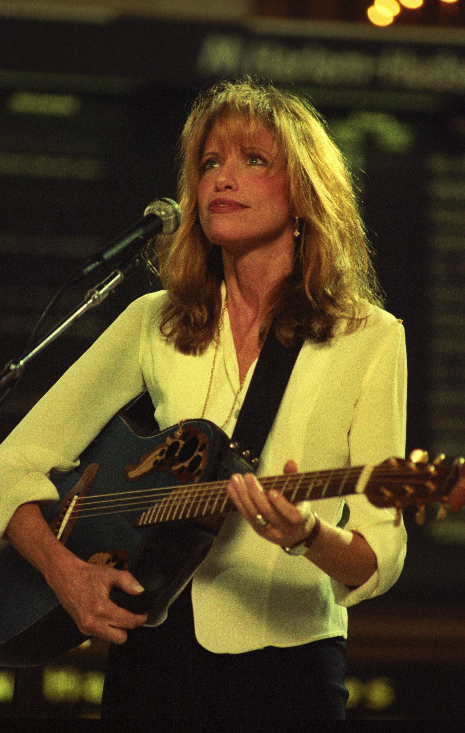 Carly Simon felt safer hibernating at home. In this photo, she played guitar while performing on stage at Grand Central Station on April 2, 1995, in New York City, New York. | Source: Getty Images
