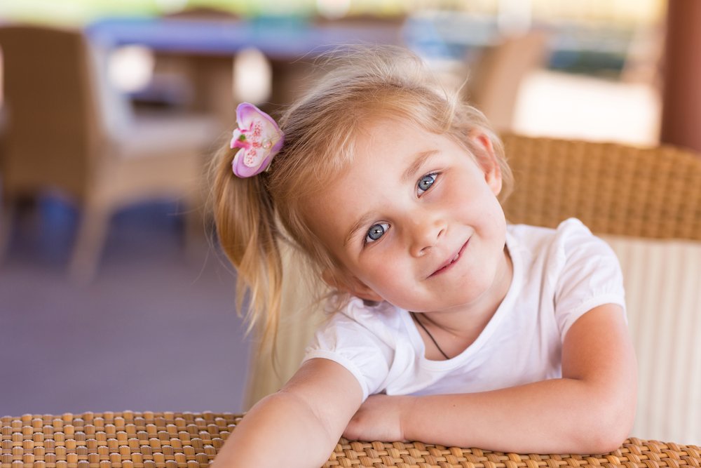 Niña sentada en una mesa mientras sonríe. | Foto: Shutterstock