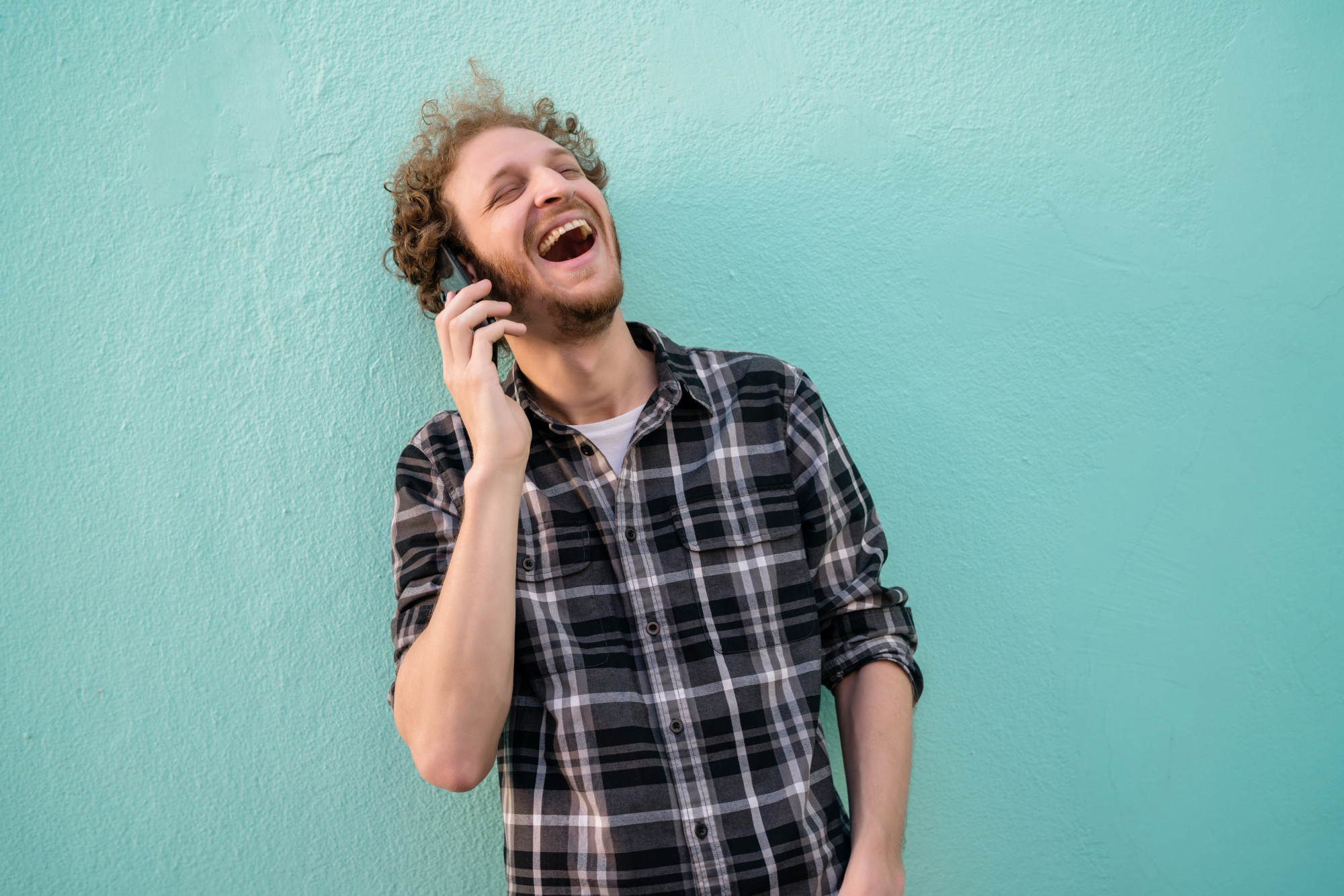 A man laughs while talking on his phone | Source: Freepik